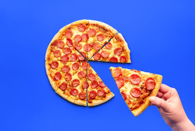 Woman's hand taking a slice of pizza, above view