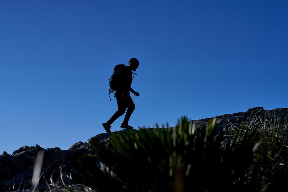 Silhouette of traveling man on rocky hill
