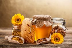Pot of honey, honey comb and pollen on wooden table 