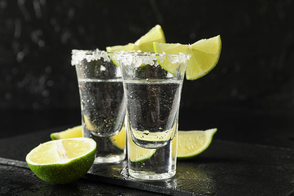 Tequila shots with salt and lime slices on dark background