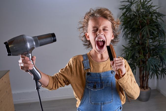 Child in a hairdresser's singing with a hairdryer and a brush