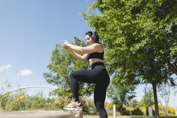 A young woman performs exercises to strengthen legs and buttocks, in a bench, during a sunny day, Zaragoza, Spain