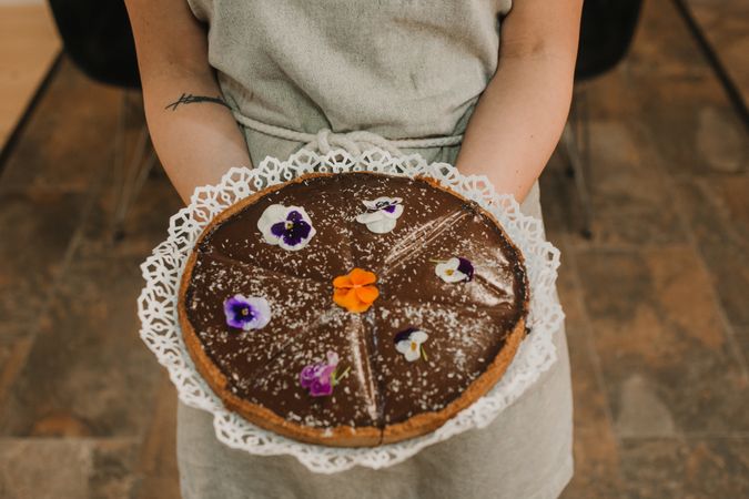 Brown pie decorated with flowers in woman hands