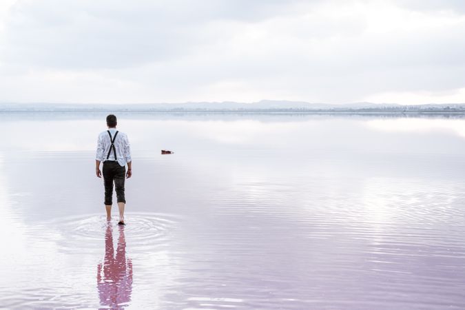 Man in wet shirt picking up guitar floating in water