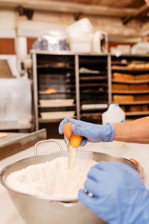 Crop cook breaking eggs into flour