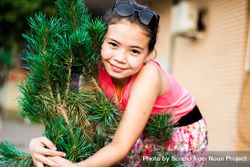 Young girl hugging small pine tree outdoor 5oB6G0