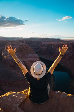 Anonymous traveler with outstretched arms near canyon