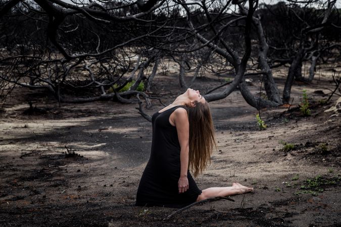 Woman posing on ground near dry trees