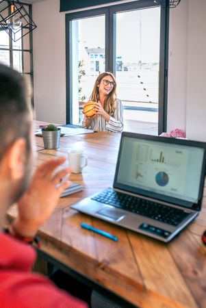 Smiling businesswoman holding small basket ball and having fun playing with colleagues in office