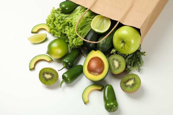 Paper bag with vegetables and fruits on blank background