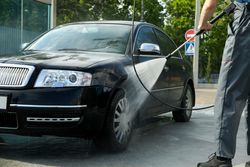 A man washes a car in a manual car wash. Clear car