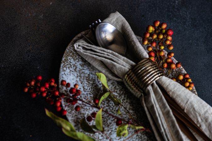 Autumnal table setting with wild red berries on grey plate