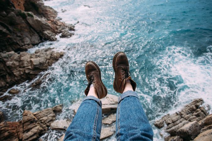 Hiker looking down at ocean in leather boots