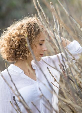 Young woman near dry twigs of bushes