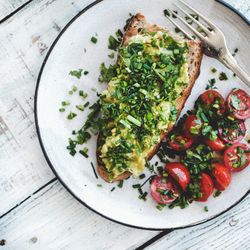 Avocado toast on sourdough bread, cherry tomatoes on light background, top view, square crop