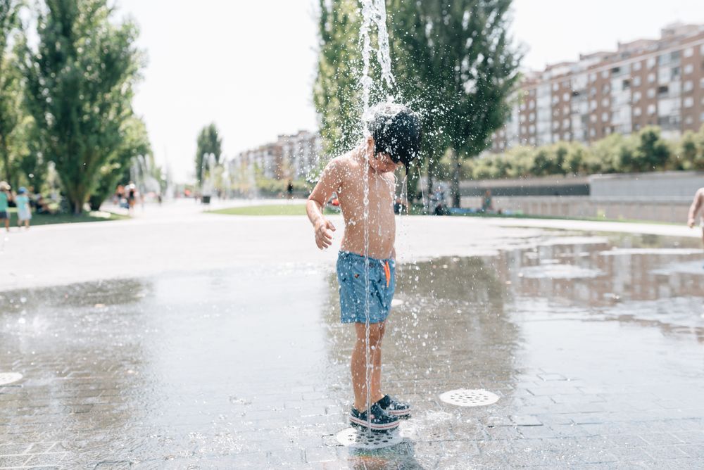 Kid standing in jet of fountain on street