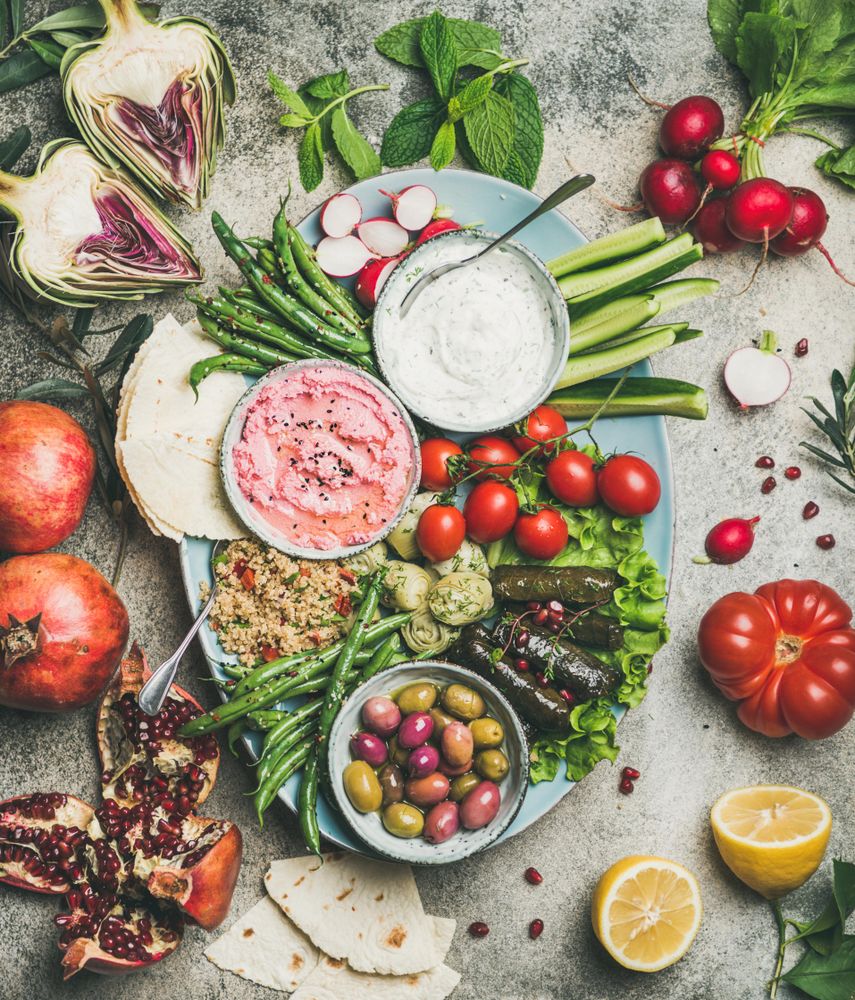 Fresh tray of vegetarian snacks with fresh vegetables, olives, hummus, and dolmas