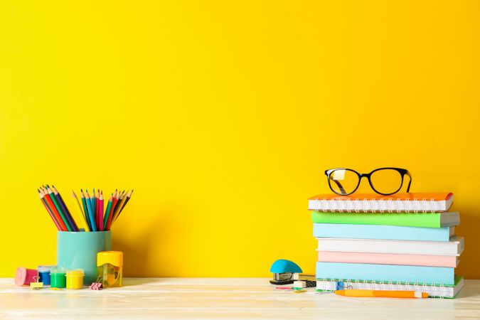 School supplies on wooden table against color background, space for text