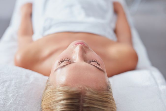 Blonde woman with eyes closed lying back and relaxing after treatment