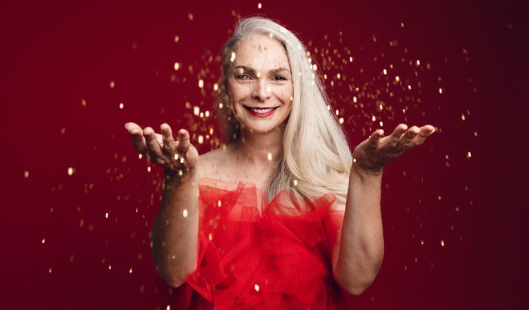 Cheerful woman in red dress throwing sparkles