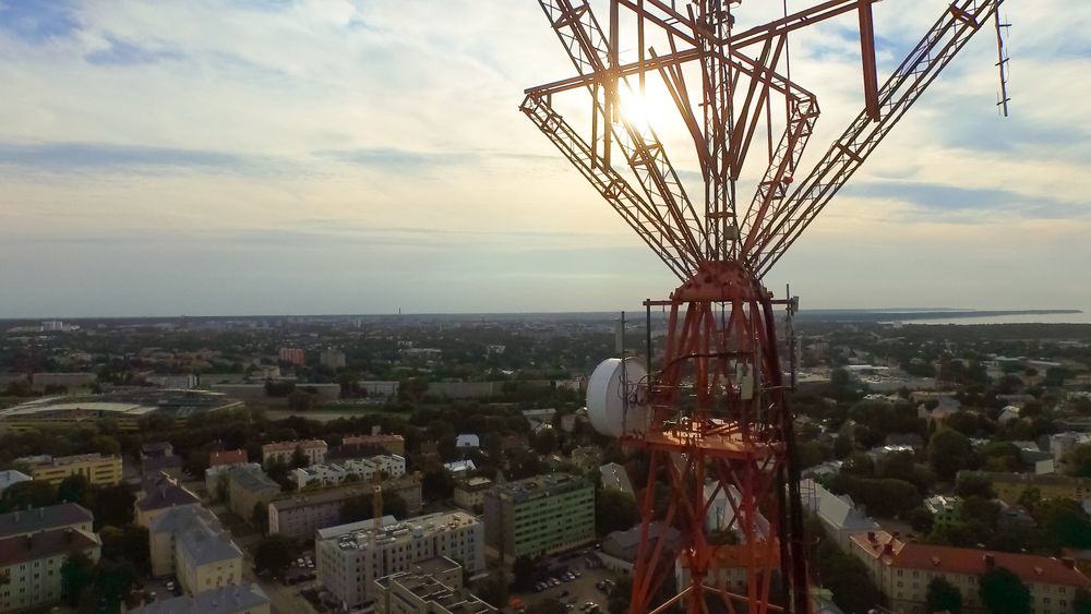 Aerial drone shot of a telecommunication radio tower mast in residential area.