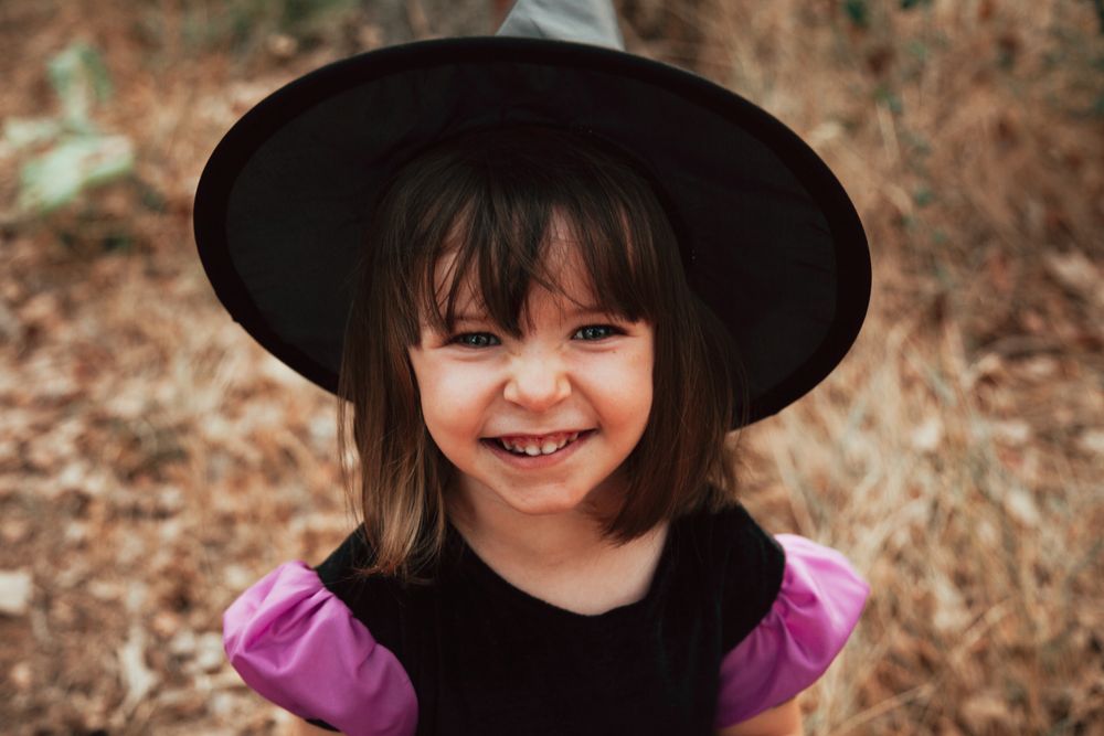 Young girl in a witch costume in a field