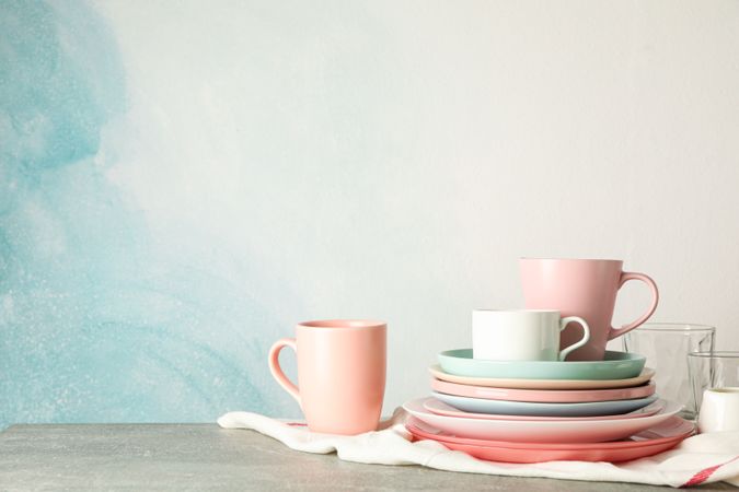 Color plates and cups stacked on grey table, space for text
