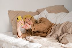 Woman on phone in bed with eye mask