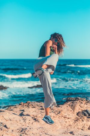 Anonymous female kicking air on seashore