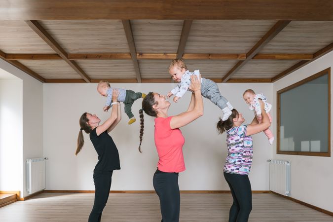 Mothers lifting babies in gym