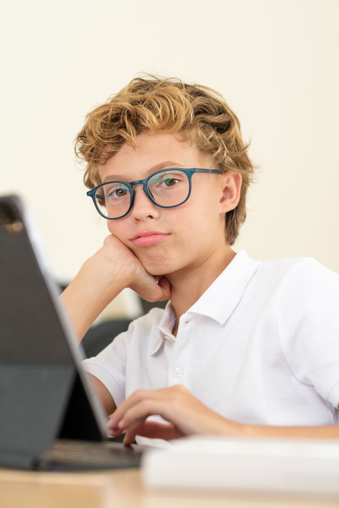 Tired schoolchild using tablet during lesson