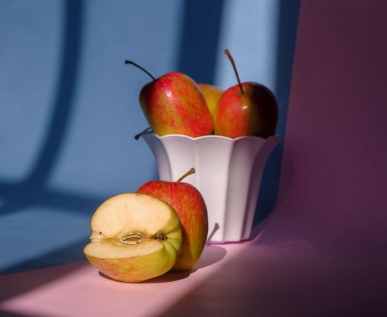Photo of an apple in a container on a pink and blue background