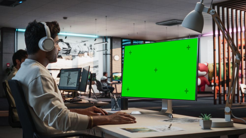 Indian Male Game Designer Using Desktop Computer With Green Screen Chromakey on Display