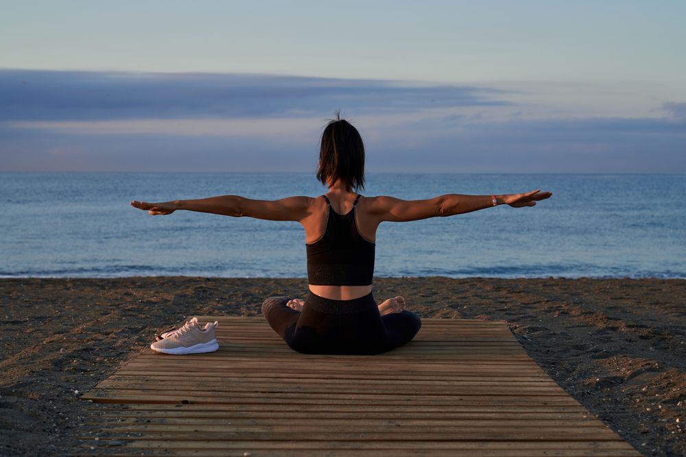 Anonymous woman doing yoga on beach