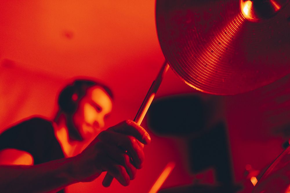 Man with drumsticks playing on drums in redness