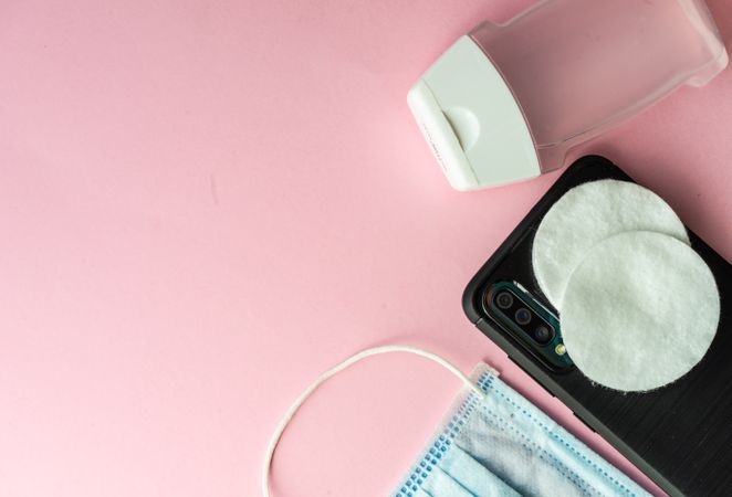 Looking down at pink table with medical supplies for cold or flu and phone