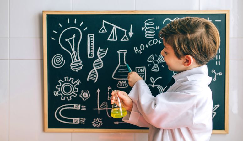 Boy dressed as chemist pointing at chalkboard