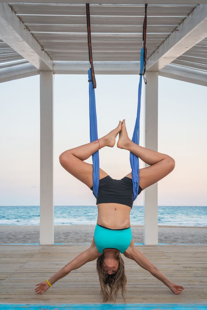 Relaxed woman performing aerial yoga hanging head down