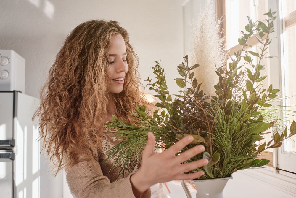 Content lady making composition of twigs at work