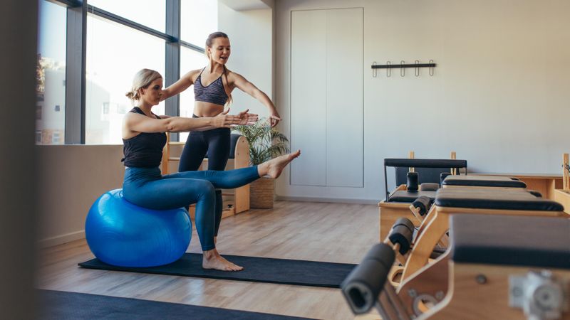 Fitness trainer guiding a woman in pilates training