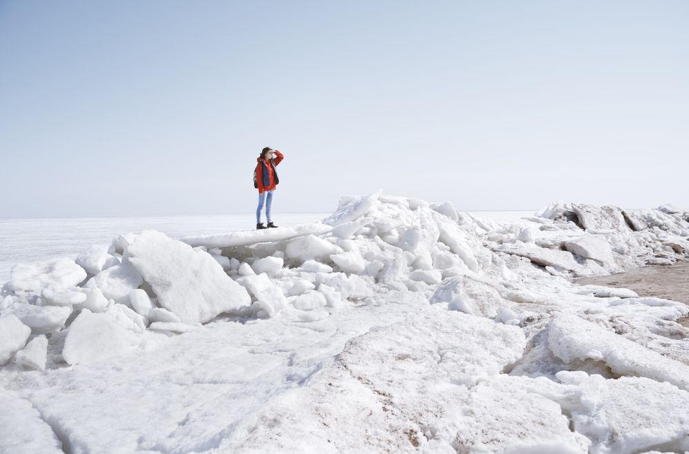 Young adult woman outdoors travelling with backpack in icy lands