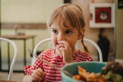 Girl eating with hand from blue bowl