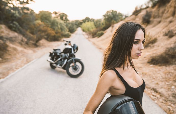 woman with helmet standing beside parked motorcycle