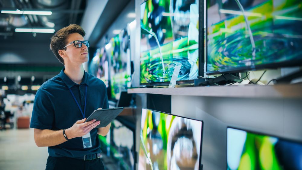Young Sales Manager in Home Electronics Store Expertly Manages Operations Using Tablet Computer.