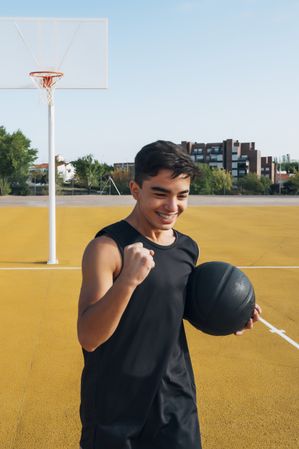 Young man playing on yellow basketball court outdoor.