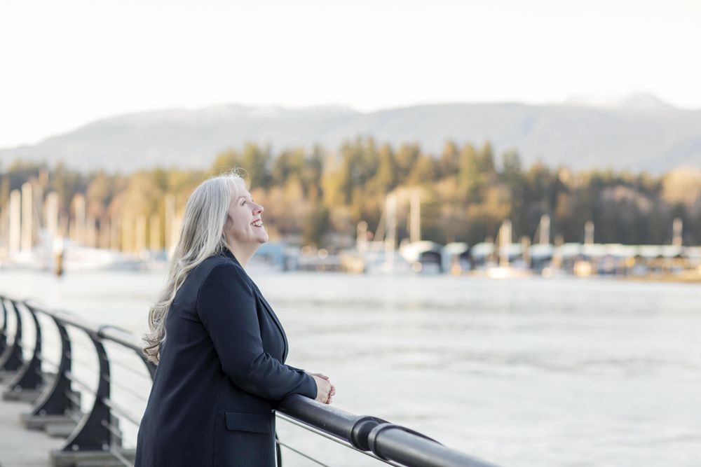 Smiling woman wearing a blazer leaning on a railing