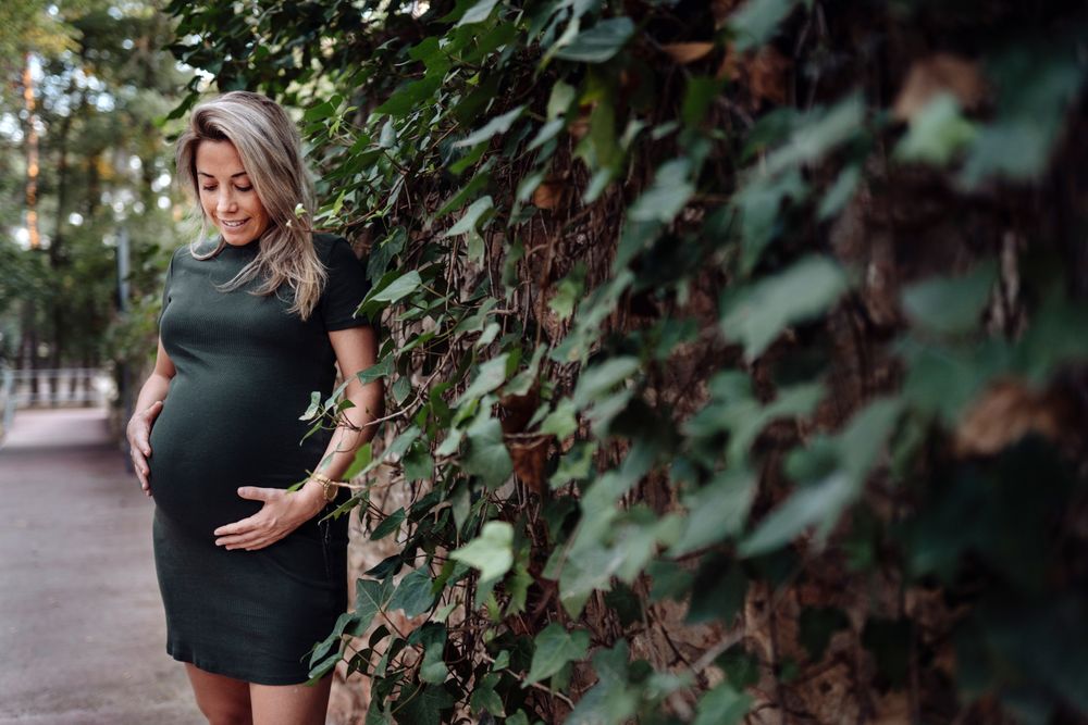 Charming pregnant woman standing on walkway in park