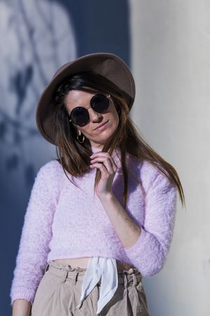 Young woman posing wearing sunglasses and hat