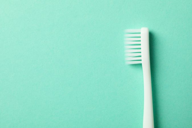 Toothbrush on mint background, space for text