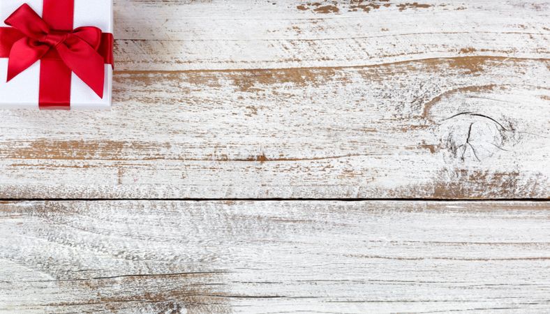 Holiday gift box in upper corner of rustic wooden background